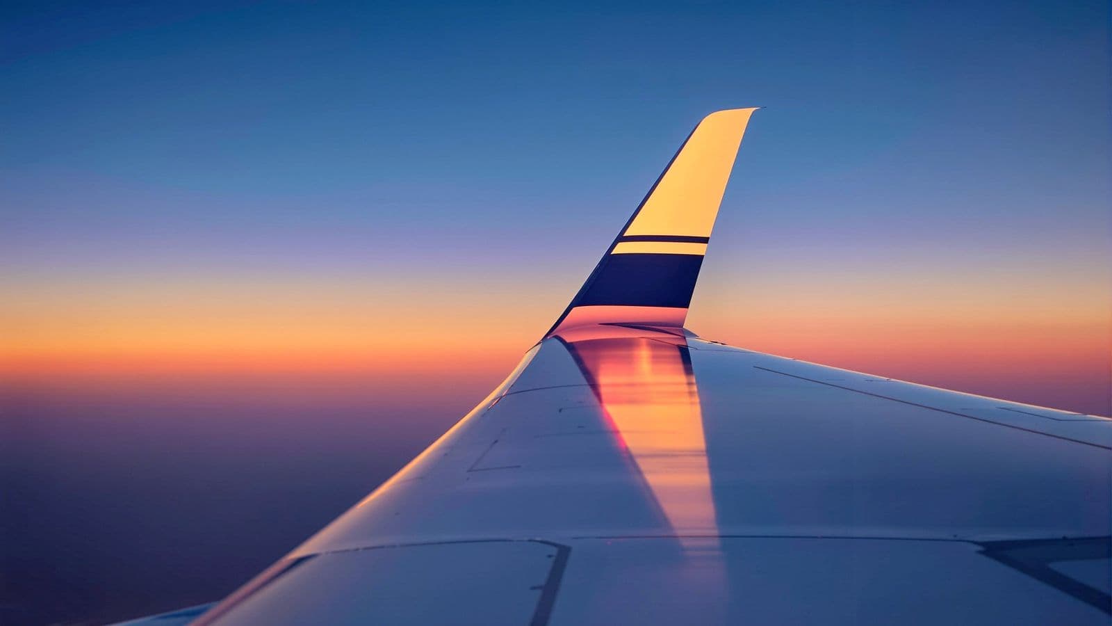 A wingtip above the clouds at dusk.
