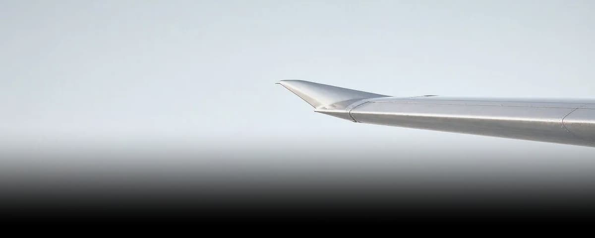 A jet wingtip against a pale sky.
